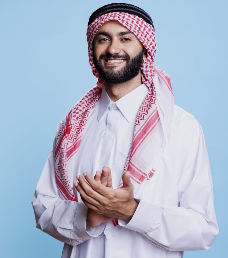 Muslim man wearing traditional clothes displaying support gesture by applauding with hands in studio. Smiling arab clapping arms and looking at camera with excited expression